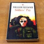 Cover of Soldiers' Pay, a 1929 novel by WIlliam Faulkner. Cover depicts a soldier wearing sunglasses, with a cross and smoke cloud in the background.