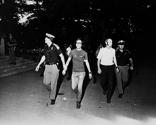 Two male students being led away by two male police officers